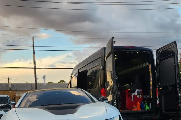 Mobile tire service on a white BMW i8 in Houston with on-site tire replacement van.